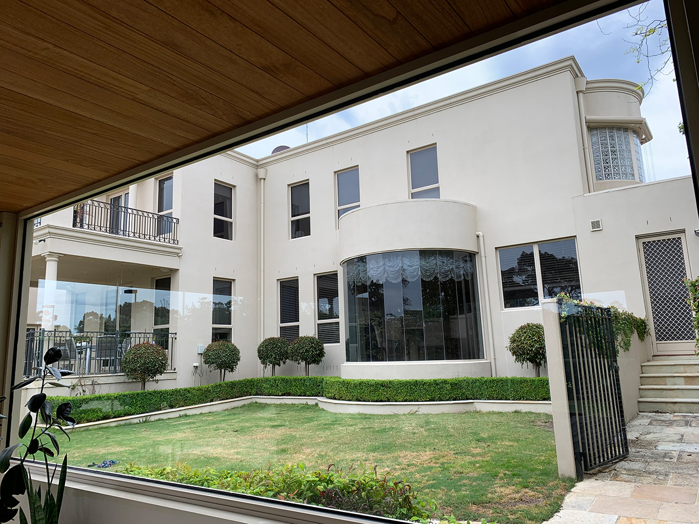 Large white home with windows overlooking a garden